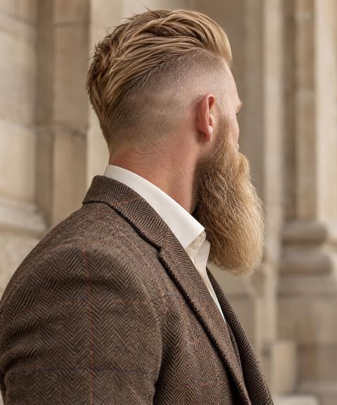 Man with a long groomed beard and undercut wearing a tweed jacket